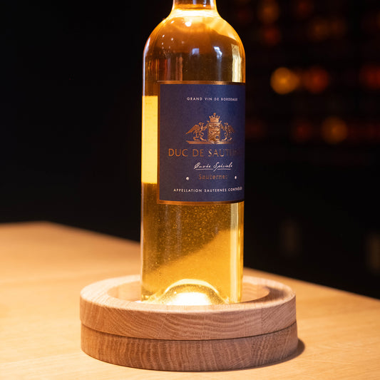 Bouteille de vin sauternes duc de sauternes posé sur une table illuminée par le support yobe light Pro avec anneau de finition yobe ring around en chêne massif