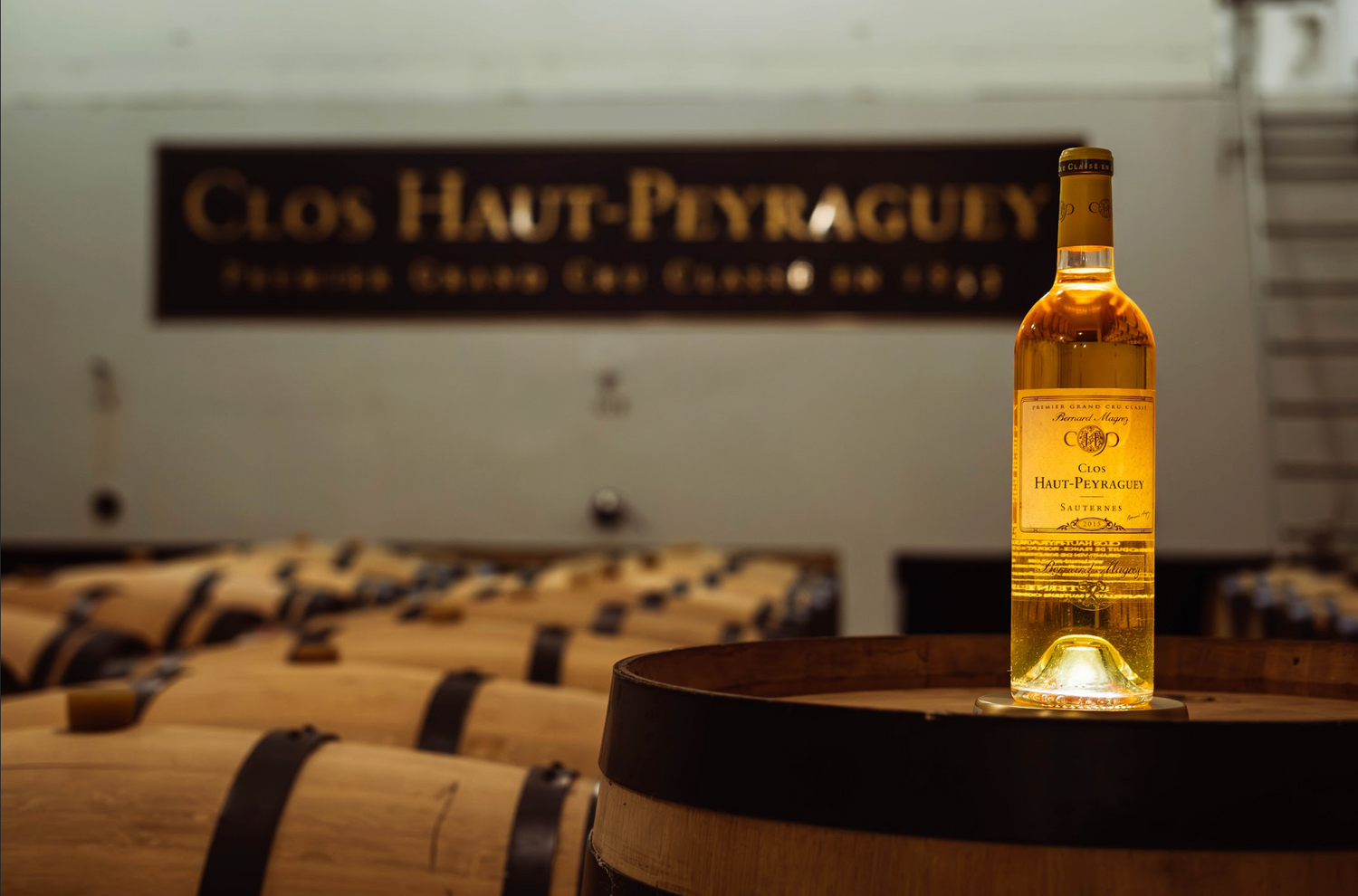 Dessous de bouteille lumineux Yobe light illuminant une bouteille de vin du Clos Haut Peyraguey Sauternes dans un chai. Retour d’expérience client sur les supports lumineux Yobe Light